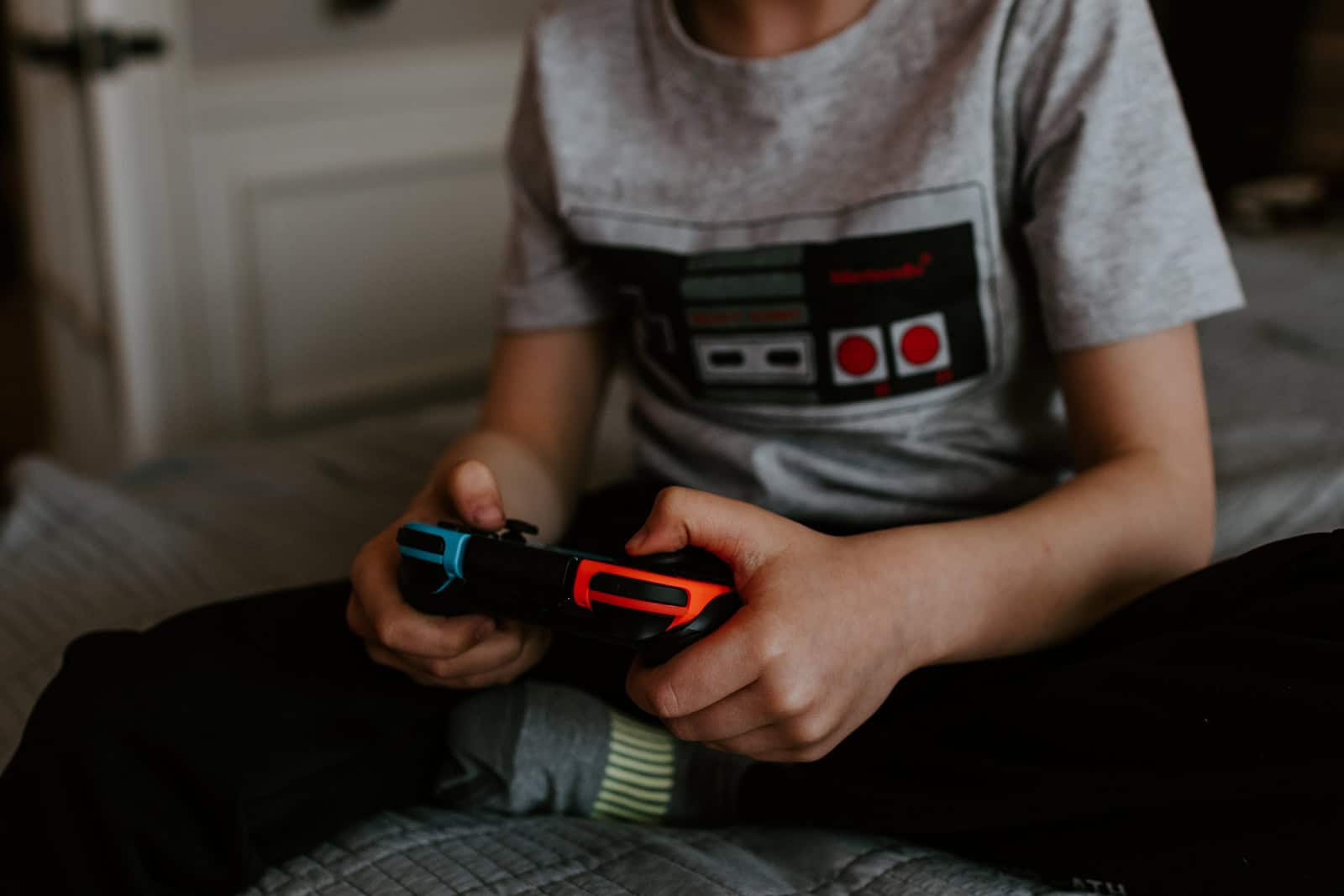 kid sitting on gray bed while playing game