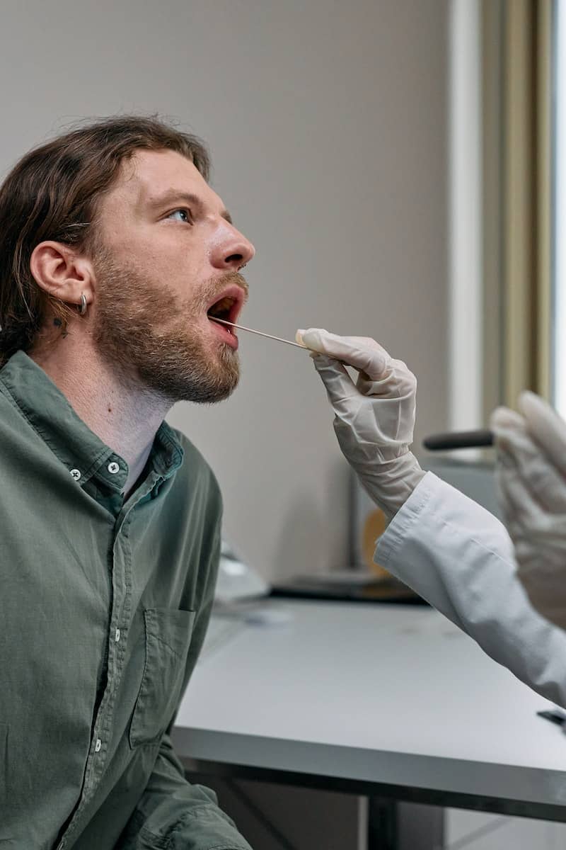 Man in Green Button Up Shirt taking a saliva test