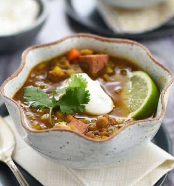 Crockpot lentil and sausage soup in white scalloped bowl