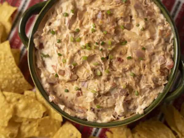 image 10083 - Are you drooling yet? Get out the napkins, because Crowd-Favorite Chicken Dip calls for all of the drools (haha)! Simply add some magical cream cheese, a spicy red onion, your favorite barbeque sauce, a bit of savory bacon, a hunk of shredded rotisserie chicken, a glob of sharp-as-a-tack cheddar cheese, and a juicy plum tomato and you will have them eating out of the palm of your hand (or maybe just the slow cooker)! With Crowd-Favorite Chicken Dip, you will be leading them around with a tortilla chip in no time. It's great to be the favorite!