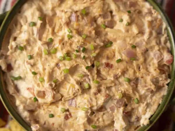 image 10087 - Are you drooling yet? Get out the napkins, because Crowd-Favorite Chicken Dip calls for all of the drools (haha)! Simply add some magical cream cheese, a spicy red onion, your favorite barbeque sauce, a bit of savory bacon, a hunk of shredded rotisserie chicken, a glob of sharp-as-a-tack cheddar cheese, and a juicy plum tomato and you will have them eating out of the palm of your hand (or maybe just the slow cooker)! With Crowd-Favorite Chicken Dip, you will be leading them around with a tortilla chip in no time. It's great to be the favorite!