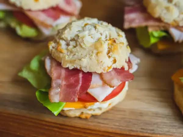 image 10543 - Club Biscuits certainly stack their flavors high! The buttery, cheesy biscuits are each filled with the classic fixings of a club sandwich: crisp lettuce, juicy tomato, savory turkey, crunchy bacon, and creamy cheese. There's something just so lovely about a good club sandwich on good bread (or in this case a good biscuit)! You'll know that's true when you sink your teeth into a couple of these Club Biscuits!