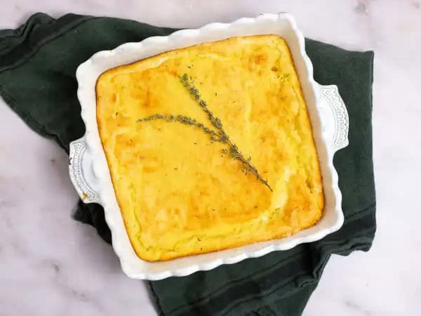 image 11478 - Special Spoon Bread Bake sounds like something that would come straight from your grandma's Southern kitchen, don't ya think? It brings a little bit of elegance with a whole lot of comfort, which really reminds us of our dear granny. This golden-brown dish is buttery, warm, and thick to create a consistency that is partially bread-like, but with a nod to a creamy soufflé. She would probably serve Special Spoon Bread Bake alongside some fried chicken, green beans, and mashed potatoes and we think that sounds like quite a delicious feast. Don't you? Make a plate and see for yourself!
