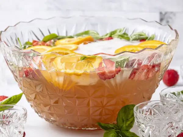 image 15314 - Fruity, refreshing, and fun, all the requirements of a tasty glass-of-class! Champagne Holiday Punch will "wow" your guests and leave them coming back for more. Orange juice and dry Champagne take center stage with cranberry juice, ginger ale, sliced strawberries and oranges, and a little basil all joining in on the punch party. 'Tis the season to celebrate in style with Champagne Holiday Punch. May all your celebrations be bright, and bubbly!