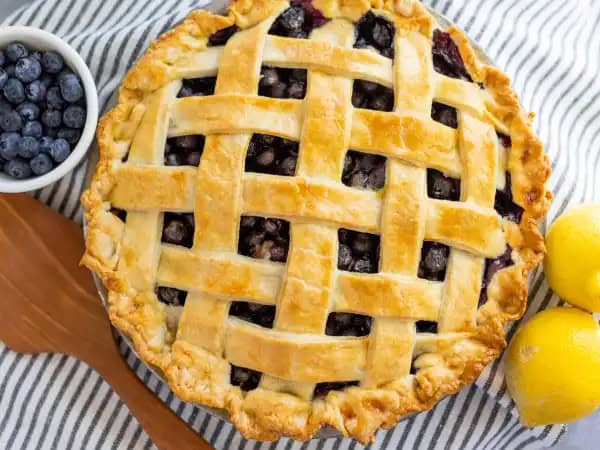 image 15630 - If there is any dessert that embodies the freedom, the beauty, and the warmth of summer, it would be a classic Blueberry Pie. The rich, tart, jammy, and sweet blueberry filling, surrounded by a golden crust with just the right amount of buttery flavor... there's nothing better, except maybe topping it with a scoop of vanilla ice cream! This Blueberry Pie isn't a challenging dessert to make and it is an instant crowd-pleaser after a cookout or just a day in the sun!