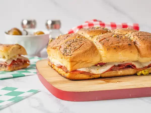 image 15741 - It's game time! These Slam Dunk Sliders are the star of the appetizer court! Layered with thin slices of ham, salami, and pepperoni, along with creamy provolone cheese, pepperoncini, and hot cherry peppers to add some spice, there really is no competition for this one! All stacked on an Italian-seasoned Hawaiian sweet roll and warmed up until golden-brown, you can count on these to be a game winning bite! Get in the game with Slam Dunk Sliders and your team will applaud your awesome efforts. Let's do this!