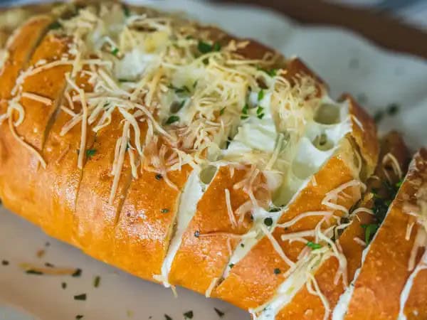 image 16121 - Is there anyone on the planet that doesn't love an herby, butter-ladened, and crusty French bread roll smooshed together with a variety of ooey-gooey, yummy melted cheeses?! Yeah, we didn't think so! You can't go wrong with this Hasselback Cheesy Bread whether you are feeding a crowd, or, um, not a crowd (we won't tell). Did we mention the melted cheeses? Like three different kinds of melted cheeses? Ah, amazing mozzarella, plus some classic white cheddar, and the perfectly-sharp parmesan, all of which create a match truly made in toasty French bread heaven! Make Hasselback Cheesy Bread anytime your crowd (or just you) craves some magnificently melodious melted cheese.