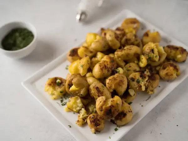 image 16190 - The easiest side dishes are the most impactful and most delicious. Take a look at these Golden Smashed Potatoes, for example. Tender potatoes boiled in savory chicken broth and rich butter, smashed flat, and then browned. Mmmm, this tasty side is flavorful, crispy, and a real winner in the potato world. Golden Smashed Potatoes are as good as gold and ready in just under 30 minutes, so they really will have an impact on your dinner menus moving forward!