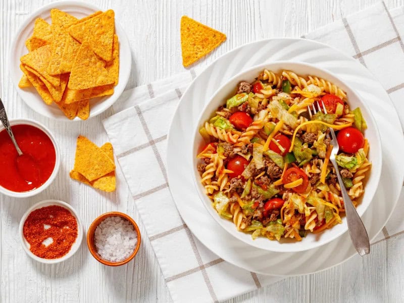 image 16817 - When it comes to any fiesta, every aspect of the party and every course being served must incorporate the Tex-Mex flavors we all love so much... that includes the sides, too! And this Cinco de Mayo Pasta Salad is sure to bring the party. Every bite is bursting with swirly, tender pasta, taco-seasoned beef, crispy veggies, salty cheese, and some poppin' Catalina dressing that will make you want to tango. You'll be movin' and groovin' to the beat of every crunch... especially while eating your favorite tortilla chips! What are you waiting for?! Let's get this party started with some Cinco de Mayo Pasta Salad!