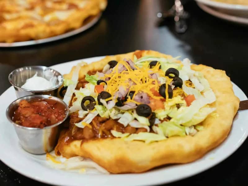 image 16893 - The state dish of Arizona, the Navajo Taco combines Tex-Mex cuisine with fry bread from Navajo tradition to create something truly amazing. The fry bread is crispy, golden brown, and buttery, the perfect foundation for juicy taco meat and all your favorite toppings. Navajo Taco only takes 40 minutes to make, so it's perfect for fun dinner parties with friends. This will be a fun new addition to your weekday meal rotation!
