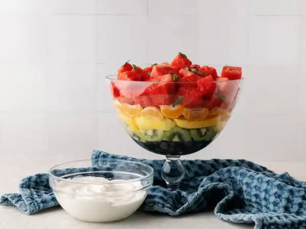 image 19592 - After every rainstorm, there comes sunshine... and sometimes we even get lucky enough to see a glimmer of glittery colors stretching across the sky. If your life is feeling more like a rainstorm metaphor and less like a bright and colorful rainbow, well then it sounds like you need a taste of this Rainbow Fruit Salad. Layers and layers of your favorite fresh and juicy fruit are piled on top of each other to add a little sweetness at the end of your meal (or the beginning, or the middle, or whenever you want, really!). There's even a fluffy, whipped, cloud-like cream for dipping or topping. Search no more, this Rainbow Fruit Salad is that glimmer of glittering colors you've been searching for, and it will certainly brighten your day!