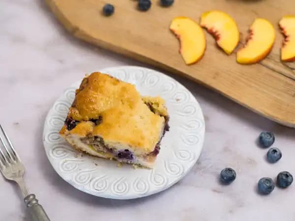 image 21168 - We've all heard of fruit-at-the-bottom yogurt, but what about Fruit-Bottom Cake? That opens up a whole new world of dessert possibilities! A tender, fluffy vanilla cake covers a layer of jammy, floral peaches, and bright, summery blueberries, so all that wonderful fruit flavor soaks into the cake! Plus, it's topped with a candied pecan crust with notes of warm cinnamon and smoky brown sugar! There's just so much to love about Fruit-Bottom Cake, you'll be amazed it can all fit on your fork!