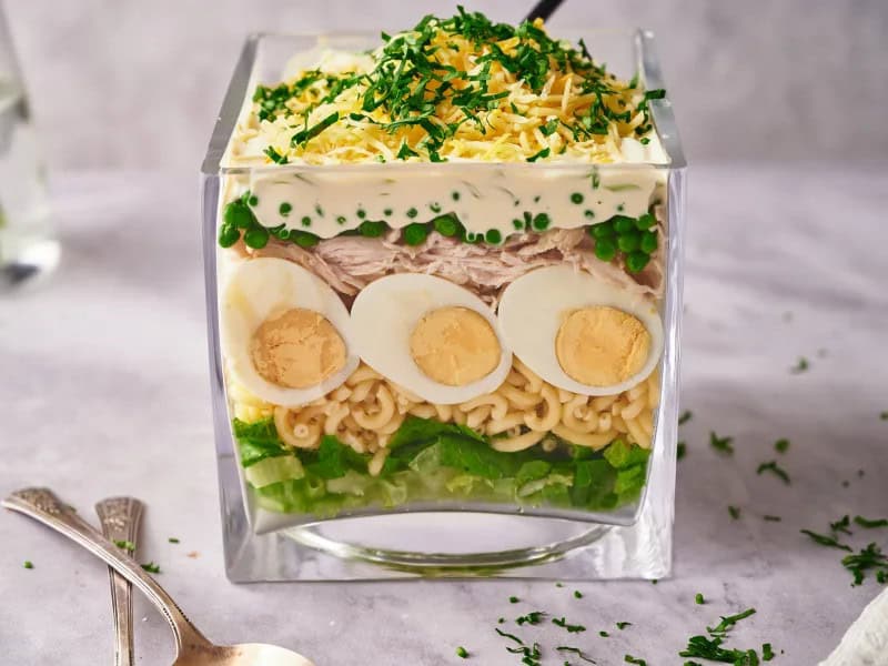 image 21973 - Ready for a deep dive into some divine flavors?! 6-Layer Salad takes you there with lots of crunch, creaminess, and contentment! When you lower your fork into this nourishing, layered creation, your tastebuds get to experience fresh lettuce, tender pasta, fulfilling hard-boiled eggs, juicy chicken, and sweet peas. But wait... that's not all! This yummy stack is topped with a creamy, tangy dressing, smooth shredded cheese, and some minced parsley to create a flavor fan out of you! 3, 2, 1, Geronimo! Jump into some fun with 6-Layer Salad!