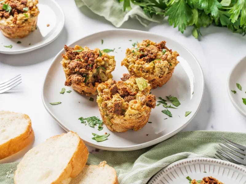 image 22276 - Stuffin' Muffins gives that boring 'ole side dish a fun twist for the better! You'll trade out your casserole dish for some muffin tins to create what appears to be a gourmet version of the traditional side. But don't worry, the production is certainly not on that level—it's so easy! You'll taste all the familiar flavors as you bite into one of these savory muffins: crunchy bread cubes, tender celery and onions, and hints of salty chicken broth. What might be new to you are the bits of spicy sausage sprinkled throughout which adds some protein and extra satisfaction! Make your meal feel a little fancier with these tender, fluffy Stuffin' Muffins!