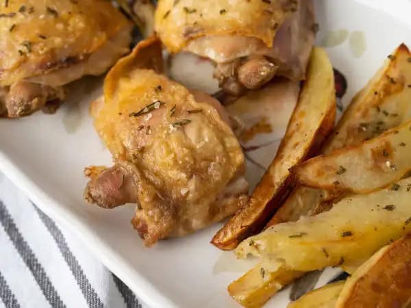 image 3468 - This is the best sheet-pan meal you'll ever taste! Roasted Chicken & Potatoes combines two of your favorite foods in a dish that comes together lickety-split! We know after a long day, it's tempting to hit up your favorite local restaurant, but why not stay at home, save a few dollars, and enjoy these juicy chicken thighs alongside some tender, herby potato wedges instead? You could even add a fresh veggie if you're feeling really wild. It all requires very little work, but brings you lots of big flavors. This delicious duo is 100% worth a bit of your time! Roasted Chicken & Potatoes are really just that good!