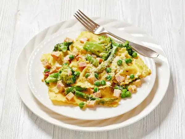 image 3968 - Greener Ravioli forgoes the scarlet of marinara to feature a more primavera theme! Everyone will find something to love in the luscious cream sauce that is dotted with emeralds of sweet peas and salty ham. Crisp-tender garden veggies help make this pasta masterpiece refreshing and nourishing with very minimal effort and certainly with speed! Greener Ravioli just changed the pasta night game!