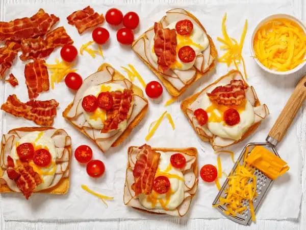 image 4035 - Whether you're hosting a garden party or having people over to watch your favorite sports team, Mini Hot Brown Sandwiches are a welcome sight! These delicious open-faced sandwiches stack the flavors high with thin slices of deli meat, melty cheese, and broiled, sweet tomatoes. Of course, it's the deliciously thick and creamy cheese sauce that is the true star of Mini Hot Brown Sandwiches; be careful, as you may be tempted to eat it with a spoon. These snacks are a breeze to make and tend to vanish just as fast!
