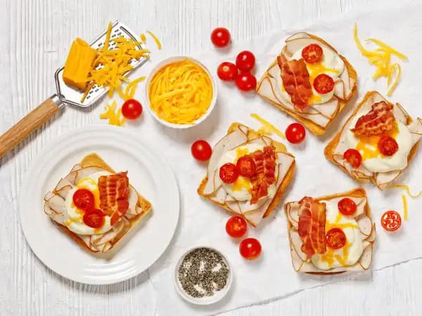 image 4039 - Whether you're hosting a garden party or having people over to watch your favorite sports team, Mini Hot Brown Sandwiches are a welcome sight! These delicious open-faced sandwiches stack the flavors high with thin slices of deli meat, melty cheese, and broiled, sweet tomatoes. Of course, it's the deliciously thick and creamy cheese sauce that is the true star of Mini Hot Brown Sandwiches; be careful, as you may be tempted to eat it with a spoon. These snacks are a breeze to make and tend to vanish just as fast!