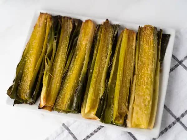 image 6062 - The crisp, savory sweetness. The subtle earthy undertones. The onion-like flavor. There are a lot of reasons to love Roasted Leeks, a humble, yet heroic, side dish that goes well with steak, chicken, pork... basically anything! Just letting the leek flavor speak for itself, accented only by salt, pepper, olive oil, and a little sharp parmesan for a touch of cheesy goodness, allows the wonderful flavor to entertain and amaze your tastebuds. Roasted Leeks will dazzle you from the first bite to the last!