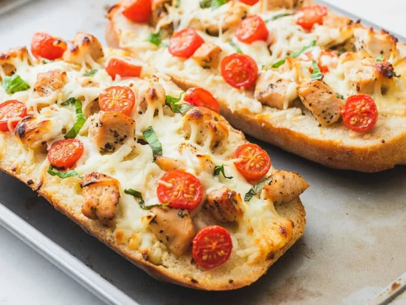 image 7803 - We've all dreamed of having fragrant, buttery, crunchy garlic bread as the main course. Cheesy Chicken Garlic Bread makes that dream a tantalizing and tasty reality. Piled with sunny and bright tomatoes, juicy browned chicken, and melty mozzarella cheese, Cheesy Chicken Garlic Bread has everything you could want out of a savory and comforting dinner. With a balsamic vinegar dipping sauce for an extra tangy flavor, you literally can't go wrong with this dish of your dreams.