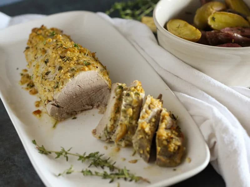image 8638 - Tender, savory pork with a golden-brown herby crust sounds like a delicious dinner that would take five hours to prepare, right? Good news! This Herb Crusted Pork Tenderloin can actually be on your table in 30 minutes or less. Juicy and with just a hint of mustard tang, this main course tastes like a special occasion but relaxes you like a weekday staple. Herb Crusted Pork Tenderloin will become a no-fuss favorite for years to come in your home.