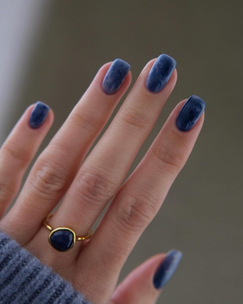 Varied blue nail designs showcasing light blue nails, royal blue acrylic nails, and blue French tips in different hand poses.