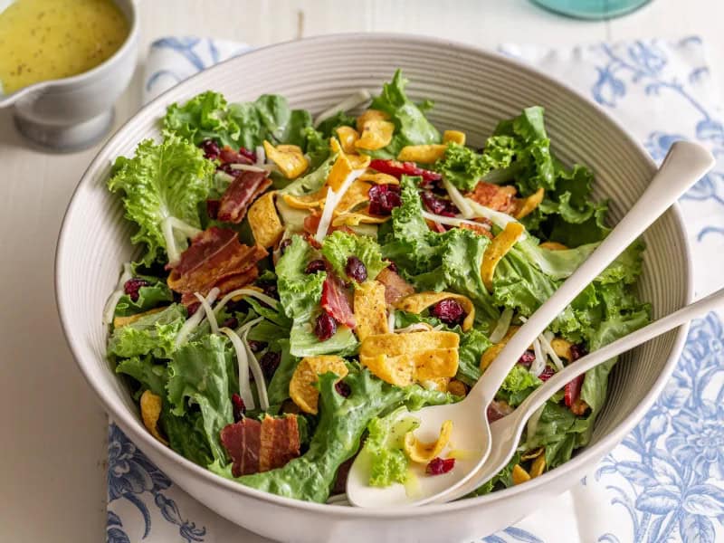 image 218 - Cha-ching! Million Dollar Corn Chip Salad brings a windfall of flavors to liven up the party and make everyone feel like a million bucks! Crisp lettuce and crunchy corn chips make each bite a boisterous and boundlessly tasty affair! Fatty bacon, creamy mozzarella, and tart-dried cranberries only add to the richness of the feast in every bowl filled with Million Dollar Corn Chip Salad. Dressed to the nines with a creamy, tangy, and sweet mixture that adds to the wealthy feeling, this is a speedy and easy party salad everyone will love. Time is money after all, and the best way to spend your time is at the party or taking a bite of this salad!