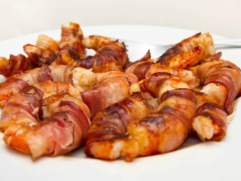 image 247 212 - Bacon-Wrapped Shrimp takes two delicious ingredients and pairs them together for a tasty, savory combination! This fan-favorite dish is sharable and simple, and you can make it for any occasion. Tender shrimp is wrapped in crispy bacon for the appetizer of your dreams! Bacon-Wrapped Shrimp is perfect for a gathering, or you can make it and save to enjoy throughout the week.