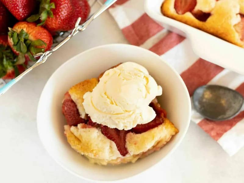 image 247 342 - Aunt Mae's Sweet Strawberry Cobbler is a long-time family favorite, and it's too good not to share! The best-kept secret about this dish is that it's super simple to whip up. Five staple ingredients are combined to create a buttery, warm cobbler base. It's baked with summery, fresh strawberries sprinkled on top to ensure you experience sweetness in every bite! Our darling aunt always ate Aunt Mae's Sweet Strawberry Cobbler with a big scoop of vanilla ice cream, so that's basically a must every time you indulge yourself!