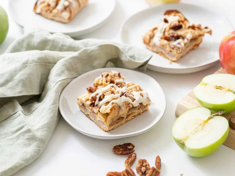 image 247 344 - Here's a treat so good you'll swear it comes from a bakery... even as you pull it from your own oven! Apple Pie Bars are everything you love in a fall-favorite dessert, in miniature form. Featuring tender spiced apples, a buttery crust, and a creamy maple-infused glaze on top, Apple Pie Bars can liven up your next party or sweeten a quiet evening in. It's an autumn confection of epic (taste) proportions!