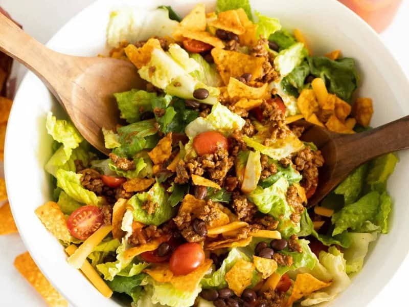 image 247 378 - Crunchy Nacho Taco Salad is here with one goal: ensure you never eat a boring salad again. To fulfill this filling mission, it combines the fresh crispness of lettuce and the juicy brightness of tomato with savory, spicy taco meat and crunchy nacho cheese tortilla chips; they certainly put croutons to shame! Crunchy Nacho Taco Salad is so speedy to put together that you'll never reach for the caesar mix again. It brings the best of Tex-Mex snack time to your salad course.