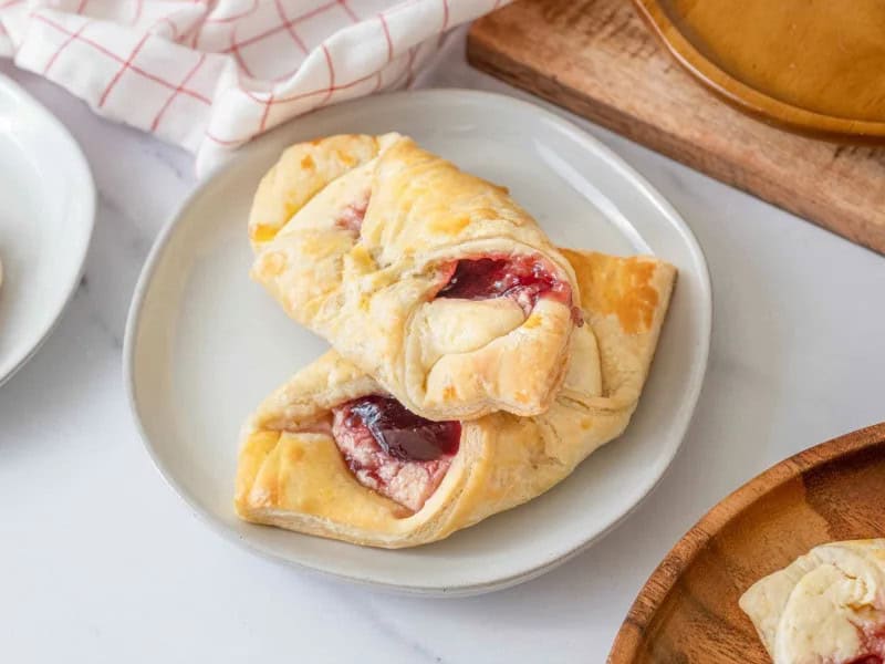 image 249 10 - If you're feeling rather dapper and want to make your breakfast spread resemble an elegant tea party, the Puff Pastry Danish is a fabulous finishing touch. The flakey, buttery puff pastries are brimming with a sweet, vanilla cream cheese filling that's topped with a spoonful of tangy, sugary raspberry jam. They're quite delectable, really. The most astonishing part is that the Puff Pastry Danish, while fancy, is low fuss, so you can punctually sip your tea, (pinkies up of course) with a perfect pastry in hand!