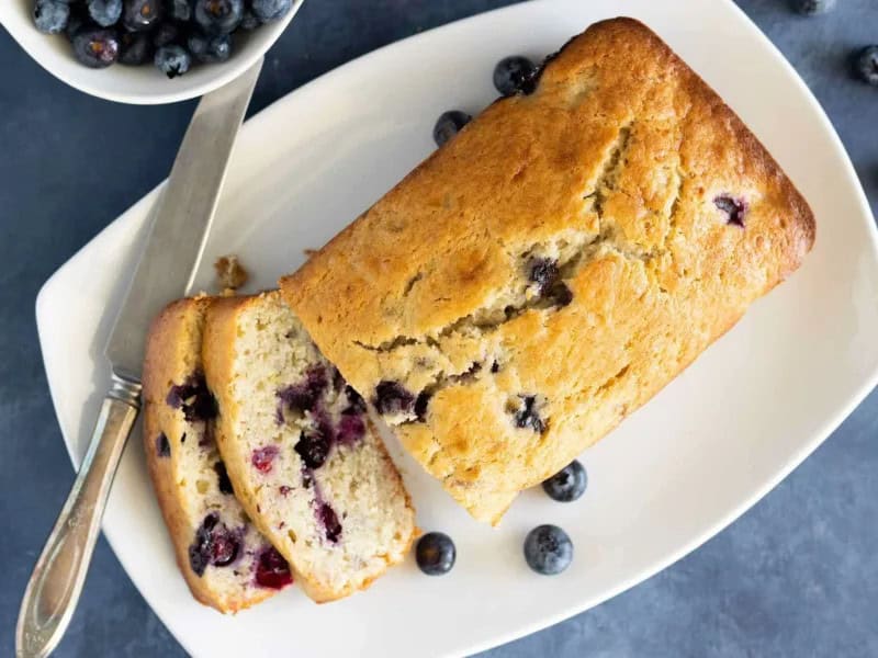 image 249 71 - Blueberry Banana Bread is about to take all your rainy day blues and turn them into rays of sunshine! This sweet, fluffy, golden-brown treat is everything beloved about original gooey banana bread, with even more fruit goodness. Fresh, beautiful blueberries are folded in to add a little pop of color and a big sensation of flavor. Warm and tasty with a hint of melty butter, Blueberry Banana Bread is a delightful treat to enjoy while the sun rises!